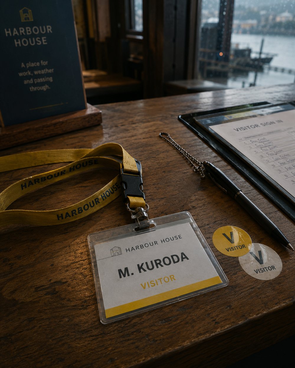 Mara Kuroda visitor badge and yellow Harbour House lanyard on a reception counter.